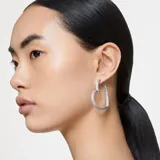 Aros grandes con forma de corazón de la familia Matrix. Diseño con engaste bañado en rodio recubierto en pavé de cristales transparentes en talla baguette.