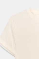 Camiseta de manga corta color marrón oscuro con textura acanalada, cuello redondo y bajo recto. Presenta un bajo superpuesto de tul o tela más clara, visible en el ruedo y en el cuello.