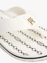 Ojotas blancas con tiras de tejido trenzado y una pequeña insignia con el monograma TH a contraste en la tira del dedo. La suela es de EVA con una línea decorativa azul marino en el borde.