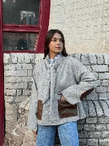 Blazer de lana gris con diseño de cuello con lazo integrado, bolsillos frontales de cuero marrón y parches de cuero a tono en los codos.
