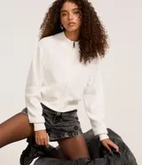 Saco de punto color blanco con cuello alto, cierre frontal por cremallera, manga larga y puños y bajo acanalados.