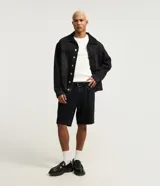 Bermuda masculina de denim negro en modelo slim con cintura fija, trabillas para cinturón, cierre tradicional y bolsillos delanteros y traseros.