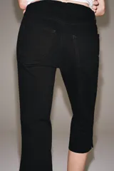Jeans capri negro de tiro medio, corte recto y diseño de cinco bolsillos. Cuenta con trabillas en la cintura y cierre frontal con cremallera y botón metálico.