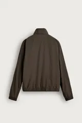 Cazadora bomber de corte relajado confeccionada en tejido técnico color negro. Presenta cuello subido, manga larga amplia, bolsillos de vivo en cadera, acabados elásticos y cierre frontal con cremallera de doble dirección.