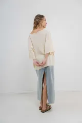 Sweater oversize de tejido liviano color blanco roto, con textura semi traslúcida, escote redondo y mangas amplias estilo murciélago.