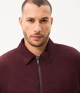 Campera bomber Marfinno para hombre, de gamuza sintética (suede) color tostado, con cuello camisero, cierre frontal metálico, bolsillos frontales y terminaciones en rib en puños y ruedo.