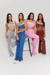 Conjunto deportivo compuesto por un top y un pantalón largo. El top es de estilo deportivo con breteles finos, escote redondo y detalle de ribete blanco en contraste, con el logo 'bk.' estampado en el frente. El pantalón es de tiro alto, ajustado en la cintura y caderas, con diseño acampanado en la parte inferior.