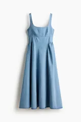 Vestido midi de denim suave, color azul claro, con escote cuadrado, espalda escotada y tirantes anchos. Presenta un cuerpo ajustado y una falda acampanada con frunces en las caderas que aportan volumen.