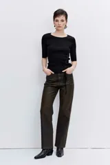 Pantalón de jean estilo wide leg con acabado engomado en tono marrón oscuro. Presenta un corte recto y holgado, con tiro medio y cierre frontal.