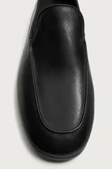 Mocasín de cuero negro con diseño liso, detalle de bordón en el empeine, horma redonda y suela ultrafina.