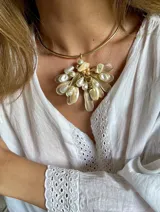 Gargantilla dorada con dije de hojas doradas, perlas y cuentas color crema.