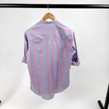 Camisa de hombre a rayas verticales anchas en celeste y rosa pálido, con cuello mao y mangas largas con puños abotonados.