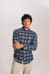 Camisa de manga larga confeccionada en tejido de franela con estampado de cuadros en tonos azul marino y verde. Presenta cuello abotonado, cierre frontal con botones y un bolsillo en el pecho con el logo bordado de la marca.