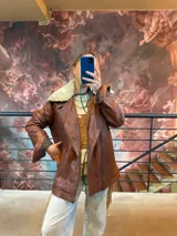 Campera de cuero ovino marrón, de corte biker, con cuello de corderito desmontable y cierre frontal cruzado.