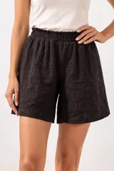 Short de tiro alto con cintura elástica fruncida, confeccionado en tela de algodón con diseño calado de flores bordadas.