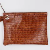 Sobre de cuero color marrón con textura tipo crocco, cierre superior con cremallera y tira de cuero con argolla metálica en el lateral.