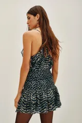 Falda corta con estampado de zigzag en tonos azul marino y beige, con detalles dorados. Presenta un canesú fruncido a la cintura y volados en el ruedo. Tiene escote en V con detalle de encaje en el borde.