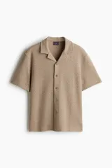 Camisa de manga corta color beige con estampado de espiga, cuello resort y corte recto.