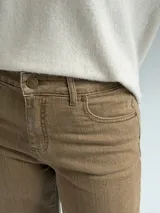 Jean de corte recto y tiro medio, en color camel con acabado desgastado. Presenta diseño clásico de cinco bolsillos, cierre frontal con botón y cremallera, y costuras reforzadas en el ruedo.