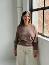 Sweater de punto color marrón, con cuello redondo, mangas largas con puños ajustados y diseño con textura acanalada vertical en el frente.