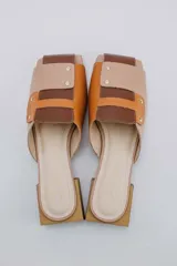 Mules de cuero color beige con detalles en marrón y suela de madera.