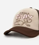 Gorra tipo trucker marca Renner, confeccionada en poliéster, con paneles frontales en color beige claro y bordado frontal con la palabra "OKAY" y detalles en marrón y rosa. Posee visera curva y laterales y parte trasera de malla respirable en color marrón oscuro.