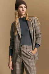 Blazer de corte sastrero con estampado de cuadros en tonos beige, marrones y rojizos. Presenta solapas clásicas, cierre frontal con un botón y bolsillos laterales con solapa.