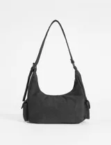 Cartera de hombro de símil gamuza color negro, con diseño de media luna, bolsillo frontal con cierre y bolsillos laterales. Cuenta con correa ajustable con ojales metálicos.