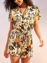 Mono corto negro con estampado floral en tonos beige y amarillo. Presenta cuello camisero, manga corta y un lazo ajustable en la cintura.