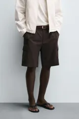 Bermuda de corte regular fit color marrón oscuro, confeccionada en tejido de lyocell y algodón. Presenta bolsillos cargo con solapa en las perneras, bolsillos delanteros y bolsillos traseros de vivo. Cierre frontal con cremallera y botón.