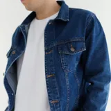 Campera de jean azul con cuello clásico, cierre frontal con botones metálicos, dos bolsillos con solapa abotonada en el pecho y dos bolsillos laterales.