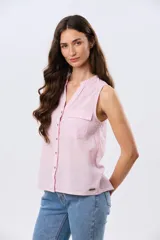 Musculosa de lino color beige, con cuello mao y escote en V, cierre frontal con botones y dos bolsillos plaqué con solapa en el pecho.