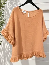 Blusa color naranja de tela liviana y fresca, con cuello redondo, mangas cortas amplias con volados y detalle de volado en el ruedo. Presenta pequeña abertura trasera con botón en el cuello.