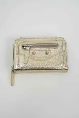 Billetera de cuero sintético color dorado con acabado metalizado, diseño tipo sobre con cierre perimetral, bolsillo frontal con cierre y detalles de tachas metálicas decorativas.