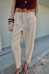 Pantalón tobillero azul marino de tiro medio, con pinzas delanteras, bolsillos frontales, falsos bolsillos con solapa en la espalda y cierre frontal con cremallera, botón y gancho. Incluye cinturón de cuero sintético tostado con hebilla metálica dorada.