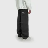 Pantalón de jean estilo ultra baggy, color negro con efecto lavado. Presenta un corte extremadamente holgado, bolsillos traseros con bordado de marca en tipografía gótica y costuras reforzadas.