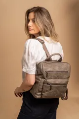 Mochila mediana de cuero sintético con textura rugosa, cuenta con dos compartimentos frontales con cierre, asa superior y correas ajustables.