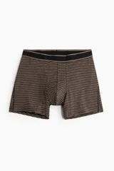 Pack de tres calzoncillos tipo trunk de algodón elástico, con cintura elástica y frente forrado. El set incluye un modelo liso negro, uno liso marrón y uno con diseño de rayas horizontales finas.