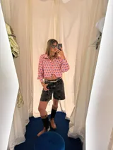 Camisa crop azul con estampado de motivos abstractos en blanco y rosa, cuello clásico y lazo en el escote.