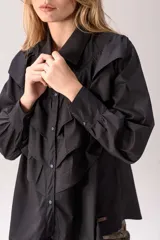 Camisa blanca de corte clásico con volados frontales y en los hombros, manga larga con puños abotonados y cierre frontal con botones.