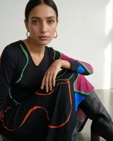 Vestido largo de corte fluido con escote en V y mangas largas. Presenta una estampa exclusiva con diseño orgánico de líneas abstractas en colores vibrantes sobre base negra.