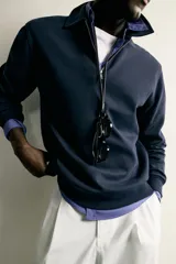 Sudadera polo de corte regular, confeccionada en tejido técnico interlock de algodón con elasticidad. Presenta cuello solapa, cierre frontal de cremallera y manga larga con puños acabados en rib.