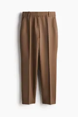 Pantalón tobillero color marrón, de tejido elástico, con cintura estándar y elástico oculto. Presenta cierre con corchete oculto, bolsillos al bies y bolsillos traseros decorativos. Las piernas son ajustadas.