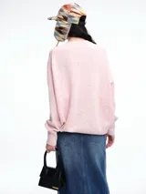 Sweater de tejido de punto en color rosa claro con motas de colores, de corte holgado, cuello redondo y mangas largas con hombros caídos.