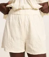 Short de cambraia color blanco, de cintura alta con elástico y bordados en la parte delantera. Tiene forro interior.