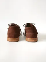 Sandalias de cuero gamuzado color marrón chocolate, diseño tipo huarache con tiras entrelazadas, tira en el empeine, talón cerrado y hebilla metálica de ajuste lateral.