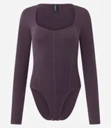 Body de manga larga confeccionado en poliamida y elastano, con diseño seamless y escote cuadrado. Presenta costuras verticales frontales que simulan un estilo corset y cierre con botones de presión en la entrepierna.
