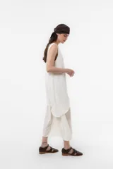 Vestido largo color tostado con silueta relajada, escote en V, sin mangas y diseño de falda en capas. Cuenta con un lazo fino regulable en la cintura.