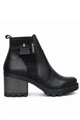 Bota de cuero color negro, de caña corta con elástico lateral y detalle de placa metálica, con taco ancho y suela dentada.