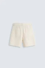 Bermuda de algodón color blanco, de corte relajado, con cintura elástica, bolsillos frontales y bolsillos traseros de plastrón. Cierre frontal con cremallera y botón.